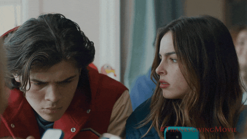 a man and a woman are looking at a cell phone and the words change saving movie are on the bottom right