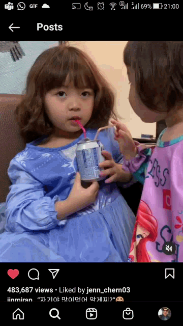 a little girl holding a can of soda with a straw in her mouth