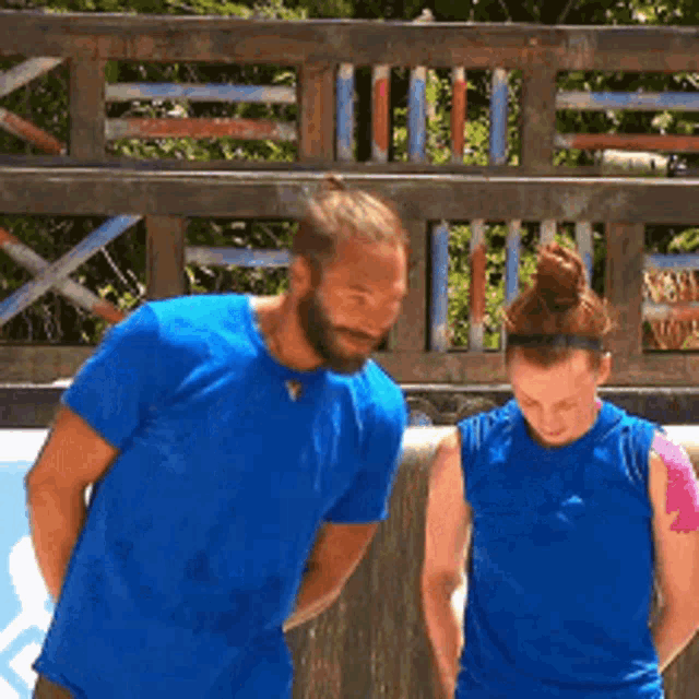 a man and a woman are standing next to each other in blue shirts