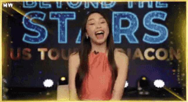 a woman in a red dress stands in front of a sign that says beyond the stars