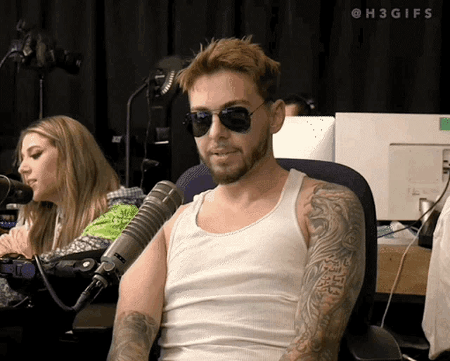 a man wearing sunglasses and a white tank top sits in front of a microphone with the hashtag #h3gifs