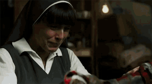 a nun is crying while holding a bloody object in her hands .