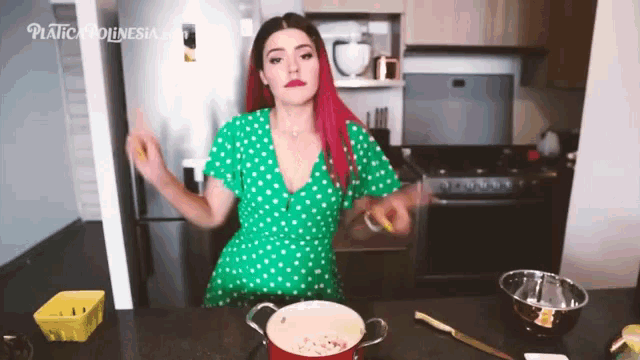 a woman in a green polka dot dress is in a kitchen