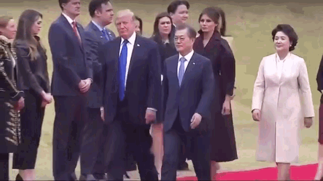 a group of people are standing around a man in a suit .