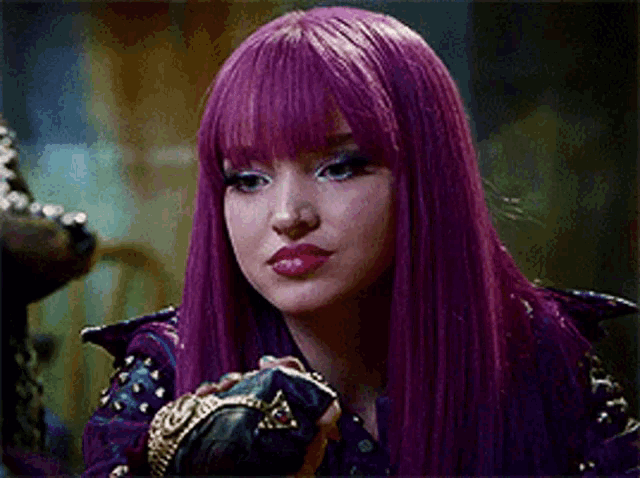 a woman with purple hair is wearing a purple jacket and gloves and making a funny face .