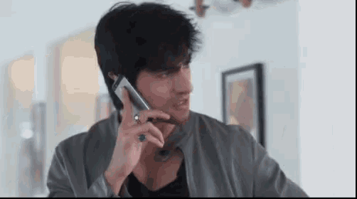 a man is talking on a cell phone in a living room .