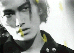 a black and white photo of a man 's face with a yellow spot on his nose