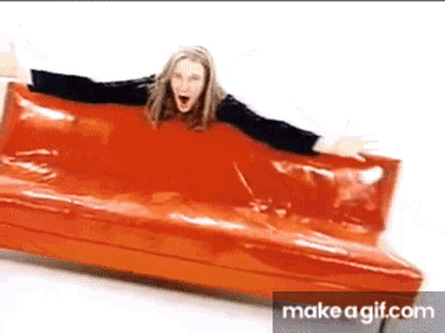 a woman is sitting on a red couch with her arms outstretched ..