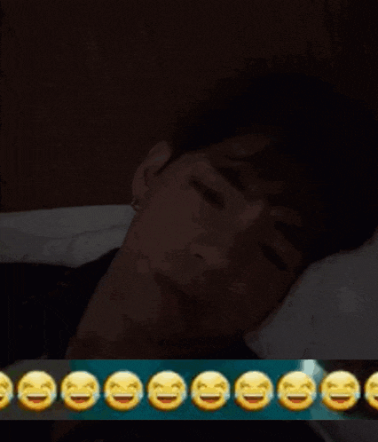 a man is laying in bed with a bunch of smiley faces behind him .