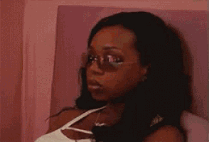 a woman wearing sunglasses is sitting on a bed .