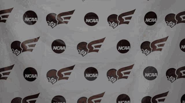 a woman holding a bat in front of a ncaa backdrop