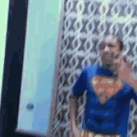 a person in a superman costume is standing in front of a wall .