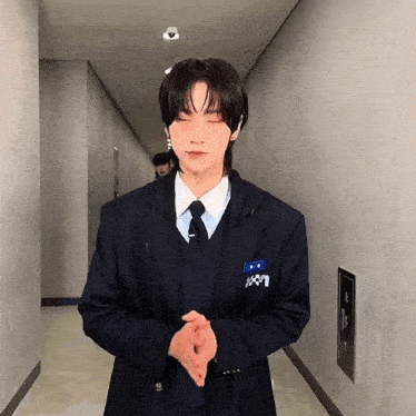 a man in a suit and tie is standing in a hallway with his eyes closed .