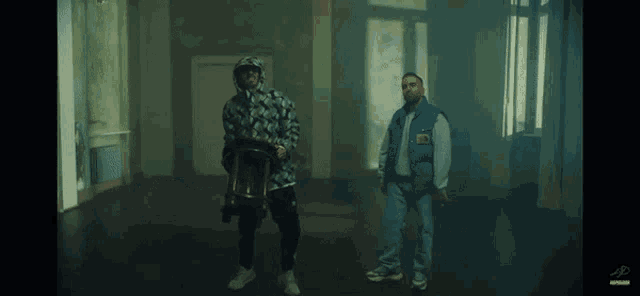 two men are standing in an empty room and one of them is wearing a blue vest with the letter p on it