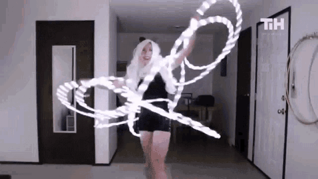 a woman in a black dress is holding a lighted rope in a living room