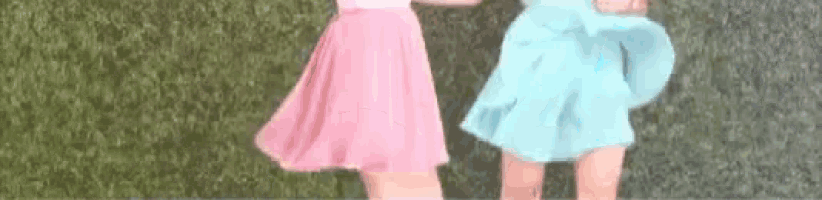 two women in pink and blue skirts are standing next to each other in front of a green wall .