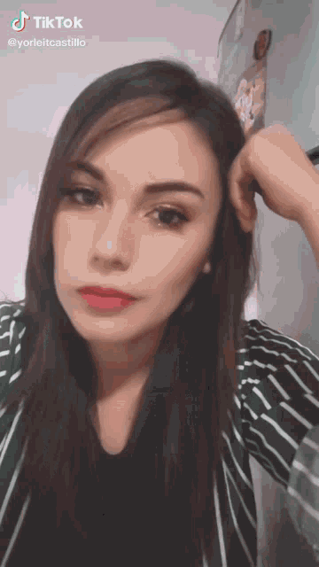 a woman in a green and white striped shirt has a tiktok sticker on her face