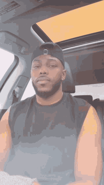 a man wearing a black hat is sitting in a car with the sunroof open