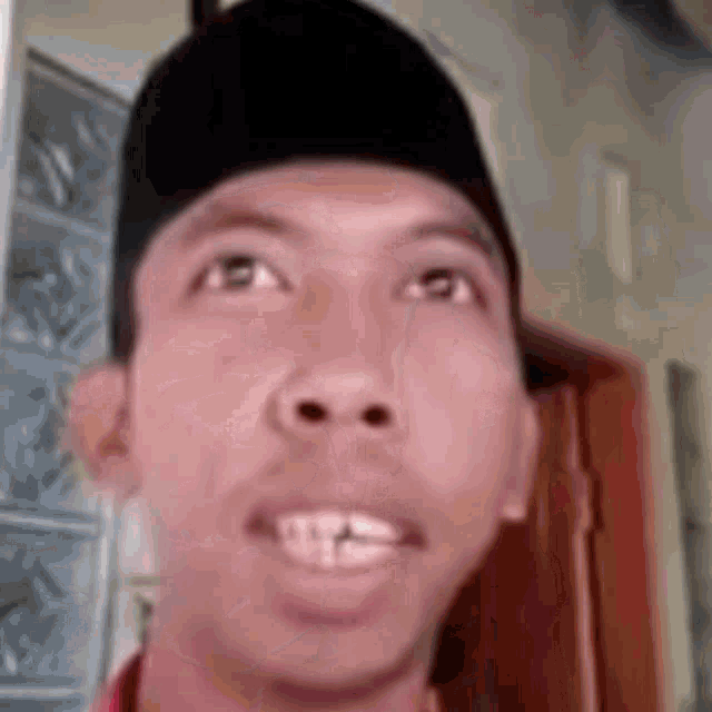 a man wearing a black hat is making a funny face while looking up .