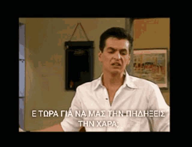 a man in a white shirt stands in front of a painting and a sign that says e topa gia na mas