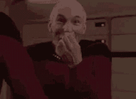 a man is laughing with his hands covering his mouth in a room .