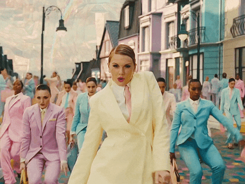 a woman in a yellow suit stands in front of a crowd of people in pink suits