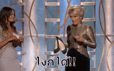 a woman is holding a pair of high heels in front of a microphone and says " i 'm a winner "
