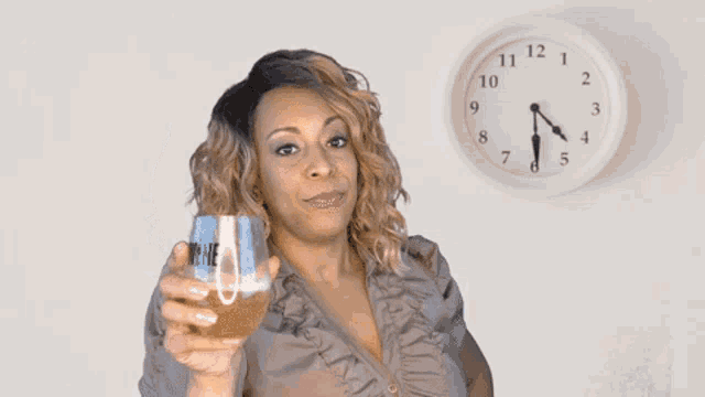 a woman drinking from a cup in front of a clock that shows the time as almost 5:00