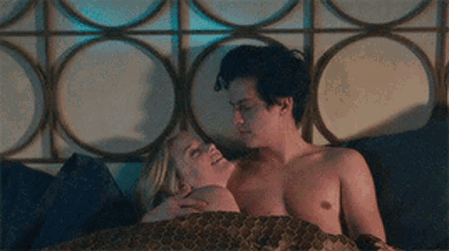 a man and a woman are laying in bed together without shirts .
