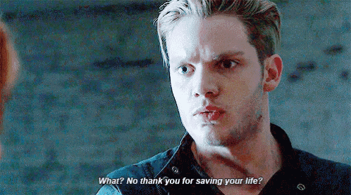 a man in a black shirt is talking to a woman and says `` what ? no thank you for saving your life ? ''