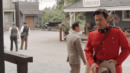 a man in a red uniform stands in front of the library
