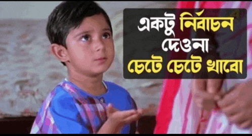 a little boy in a blue shirt is making a funny face while sitting on a bed .