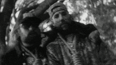 two men are standing next to each other in a tree in a black and white photo .