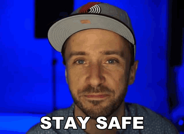 a man wearing a hat says " stay safe " in front of his face
