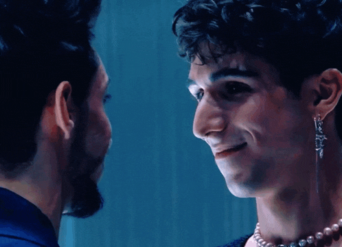 two men are looking at each other and one has a pearl necklace