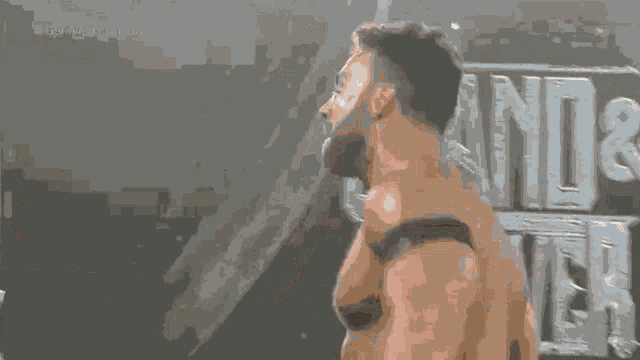 a shirtless wrestler stands in front of a sign that says " land & deliver "