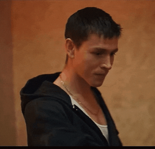 a man wearing a hoodie and a necklace is smiling .