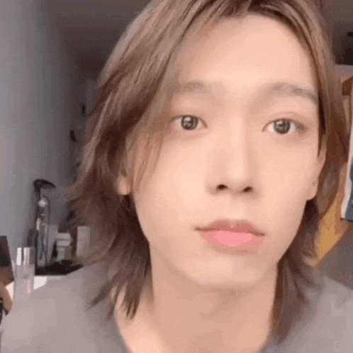 a close up of a person 's face with long hair and a pink lip .