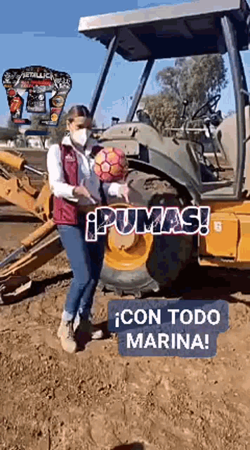 a woman in a mask holds a soccer ball in front of a bulldozer that says pumas