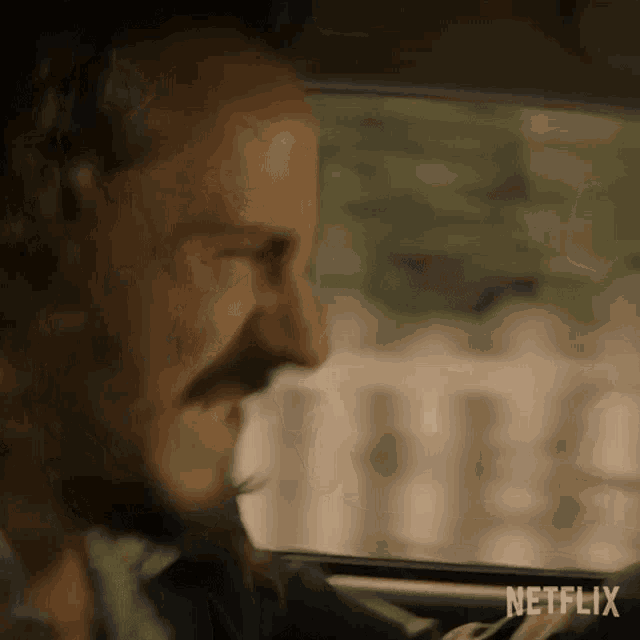 a man with a beard is driving a car with his mouth open .