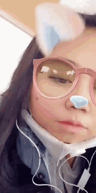 a girl wearing glasses and headphones is wearing a cat ear filter .
