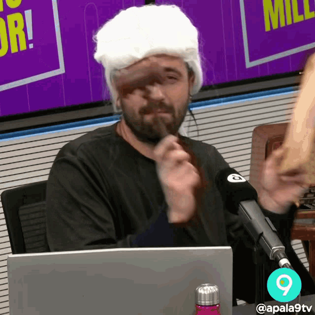 a man wearing a white wig is sitting in front of a laptop computer