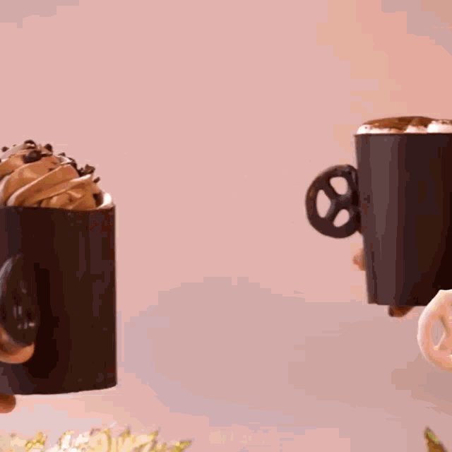 a person holding a cup with a pretzel handle and a cup with whipped cream