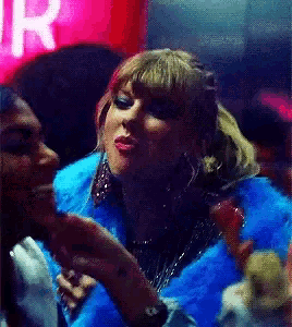 a woman in a blue fur coat is dancing with another woman