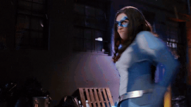 a woman in a blue and white superhero costume is holding a blue object