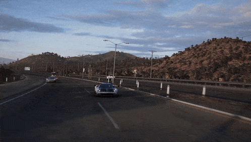 a few cars are driving down a highway with a mountain in the background