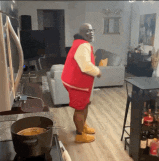 a man in a red vest and shorts is dancing in a living room