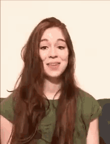 a young woman with long red hair is sitting on a couch and smiling .