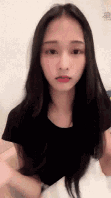 a woman with long black hair is wearing a black t-shirt and red lipstick .