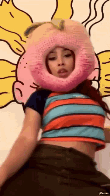 a woman wearing a pink peach hat is dancing in front of a cartoon wall .